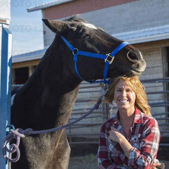 Caucasian woman smiling with horse on ranch