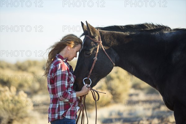 Caucasian woman hugging horse in field