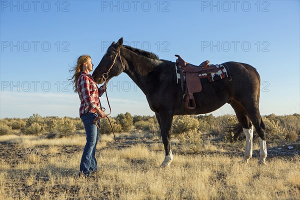 Caucasian woman standing with horse in field