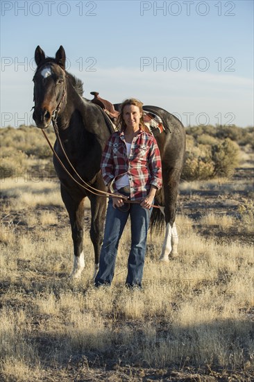 Caucasian woman walking horse in field