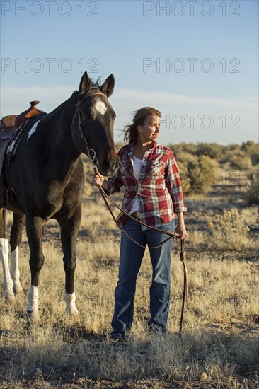 Caucasian woman walking horse in field