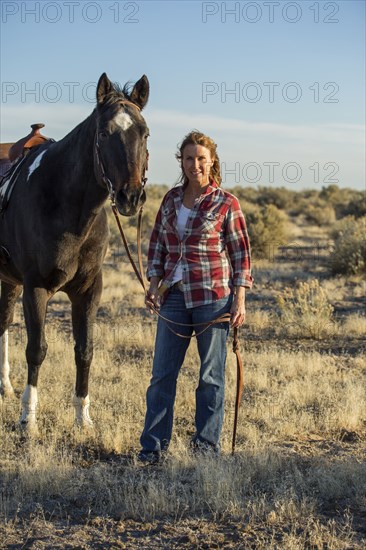 Caucasian woman walking horse in field