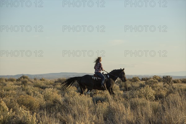 Caucasian woman riding horse in field