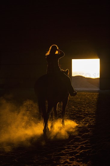 Caucasian woman riding horse in barn