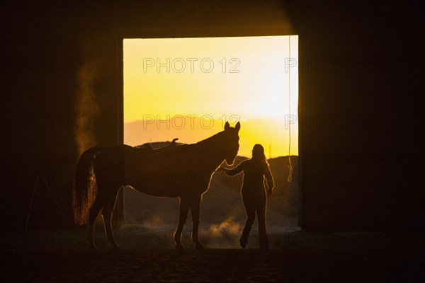 Caucasian woman riding horse in barn