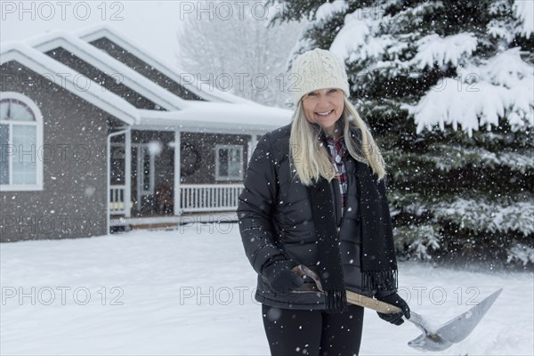 Older Caucasian woman shoveling snow in front yard