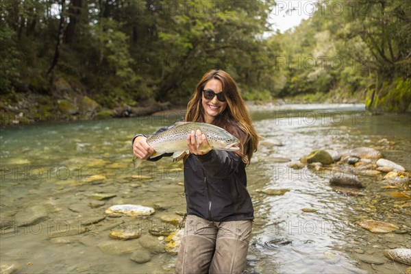 Caucasian woman catching fish in remote river