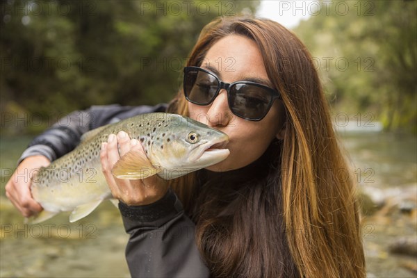 Caucasian woman kissing fish in remote river