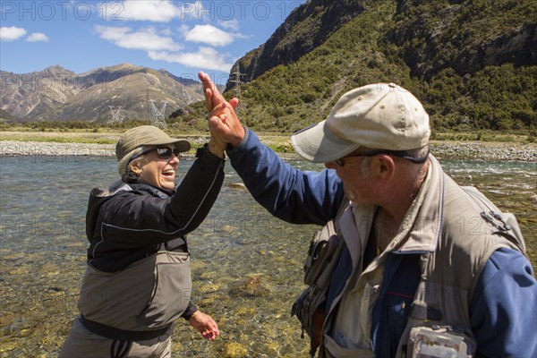 Caucasian couple high-fiving in remote river