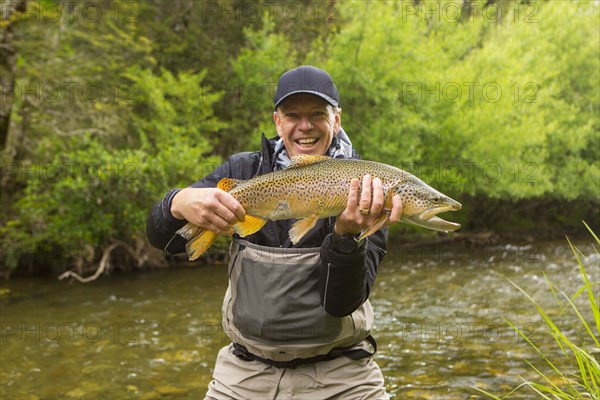 Caucasian man holding fish in remote river