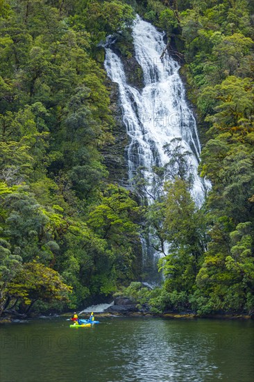 Caucasian friends paddling kayak under remote waterfall