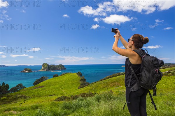 Caucasian hiker photographing cliff and seascape