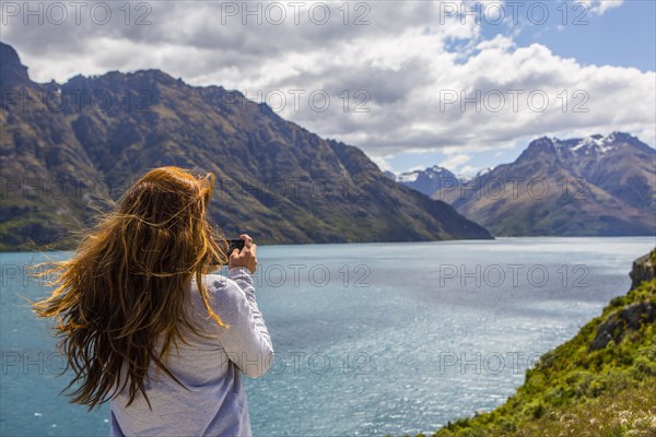 Caucasian woman photographing mountains and lake