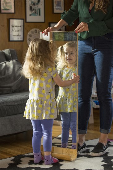 Caucasian mother showing daughter reflection in mirror