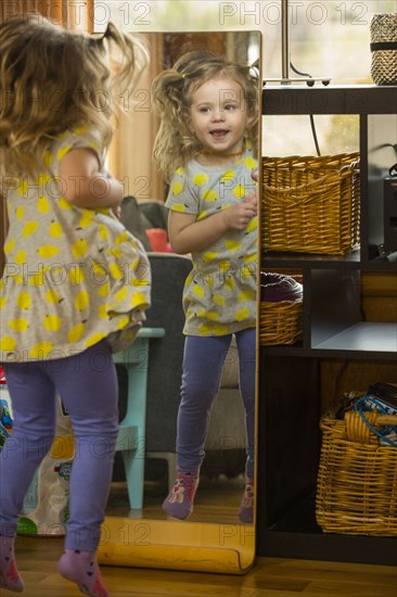 Caucasian preschooler girl admiring herself in mirror