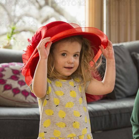 Caucasian preschooler girl playing dress-up with hat