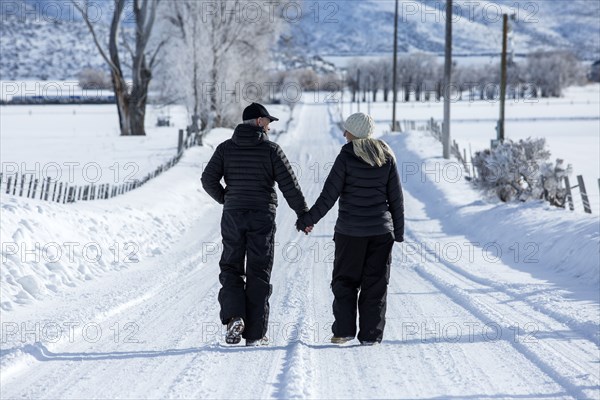 Caucasian couple walking on snowy remote road