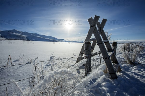 Sunrise over fence in snowy rural landscape