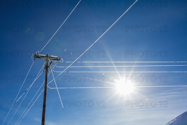 Sun in blue sky and frosty power lines