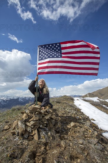 Caucasian woman planting American flag on remote hilltop