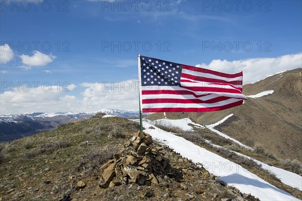 American flag waving from pile of rocks on mountain