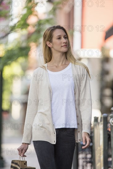 Caucasian woman carrying shopping bag in city