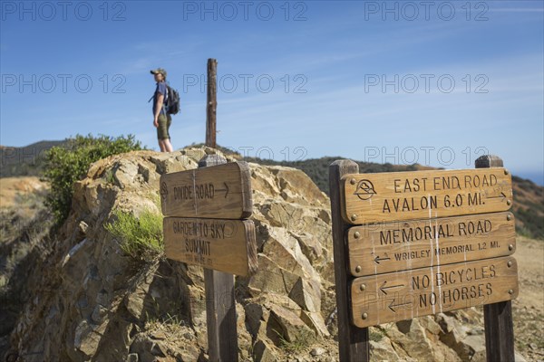 Caucasian hiker standing on rocks behind signs