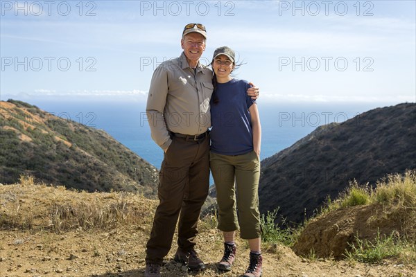 Caucasian man and daughter hugging on mountain