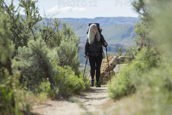 Older Caucasian woman hiking with backpack on path