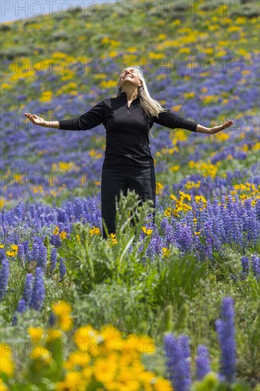 Caucasian woman smiling on hillside with wildflowers