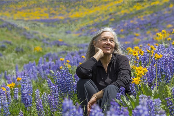 Caucasian woman smiling on hillside with wildflowers