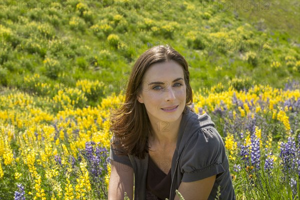 Caucasian woman sitting on hillside with wildflowers