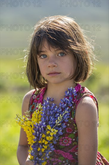 Serious Caucasian girl holding bouquet wildflowers