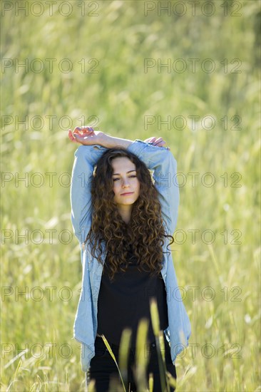 Caucasian woman with arms raised standing in field of tall grass