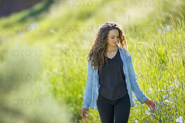 Caucasian woman walking in field of tall grass