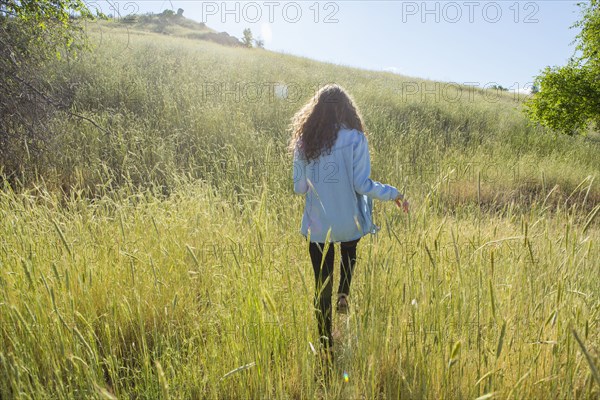 Caucasian woman walking in field of tall grass