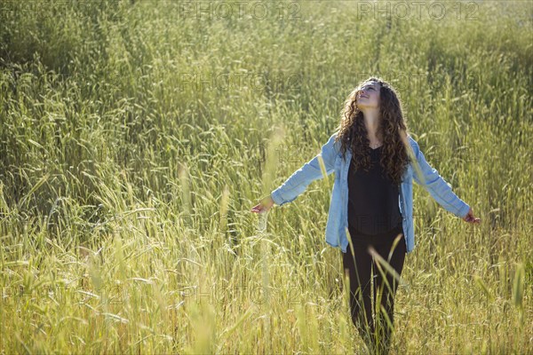 Carefree Caucasian woman walking in field of tall grass