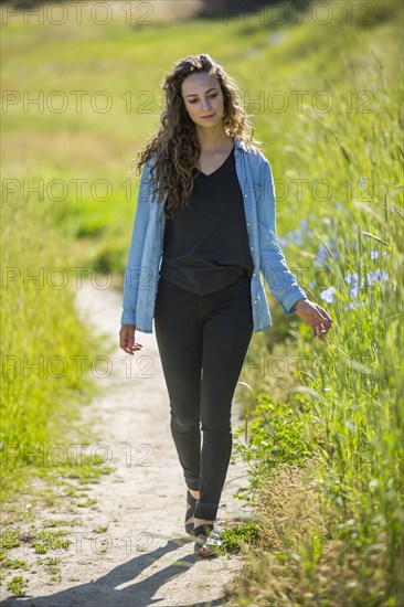Caucasian woman walking on path near tall grass