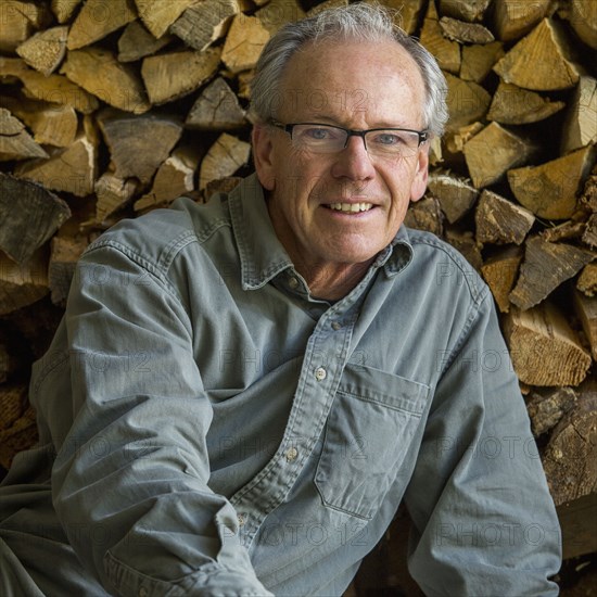 Caucasian man leaning on woodpile