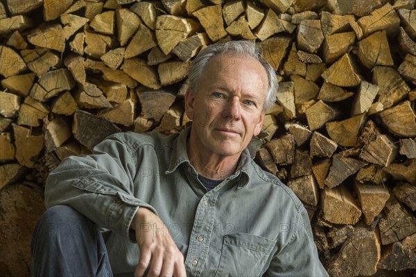 Caucasian man leaning on woodpile