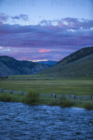 River near rolling landscape at sunset