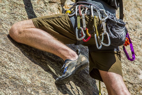 Carabiners on Caucasian man climbing rock