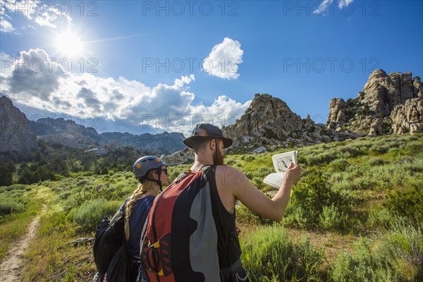 Caucasian couple reading guidebook near mountain