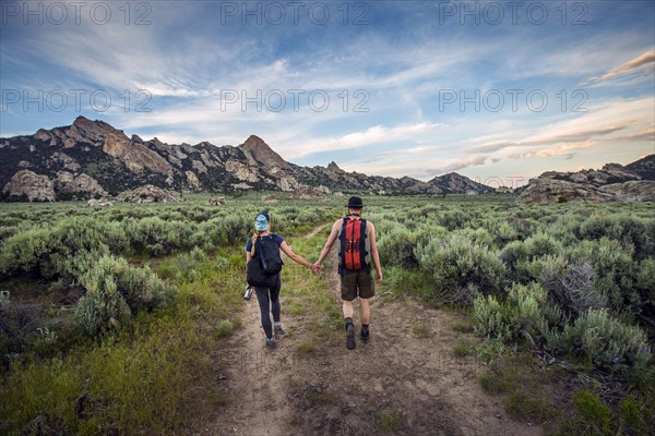 Caucasian couple hiking toward mountain