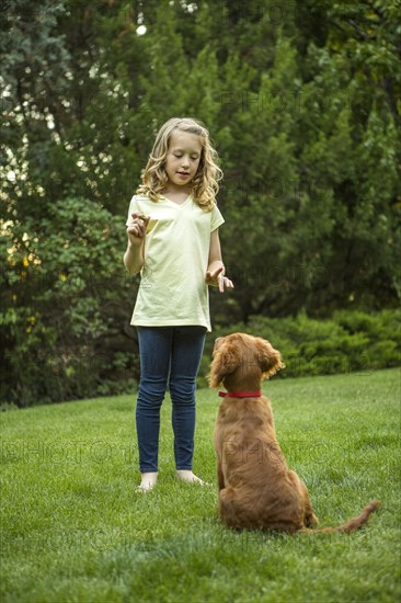 Caucasian girl training dog in grass