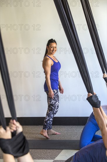 Instructor watching yoga students hanging from silks