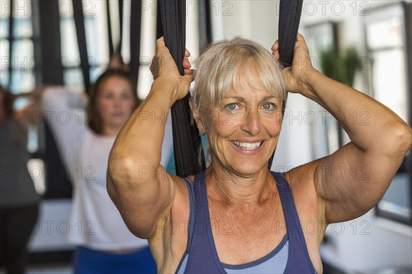 Caucasian woman performing yoga hanging from silks