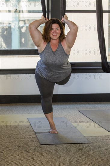 Woman performing yoga hanging from silks