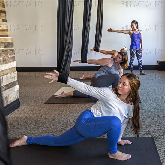 Instructor watching students hanging arms from silks