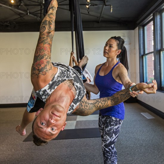 Instructor assisting student hanging from silks